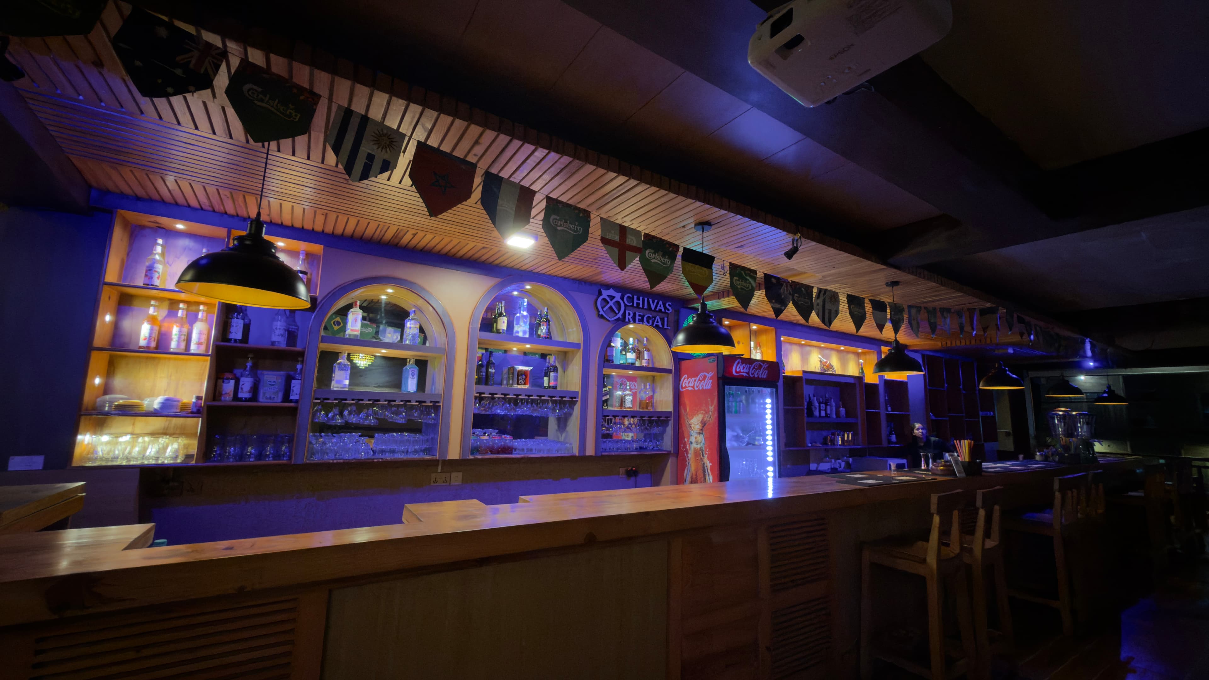Arched niches behind the bar, with glassware beneath a pendant lamp