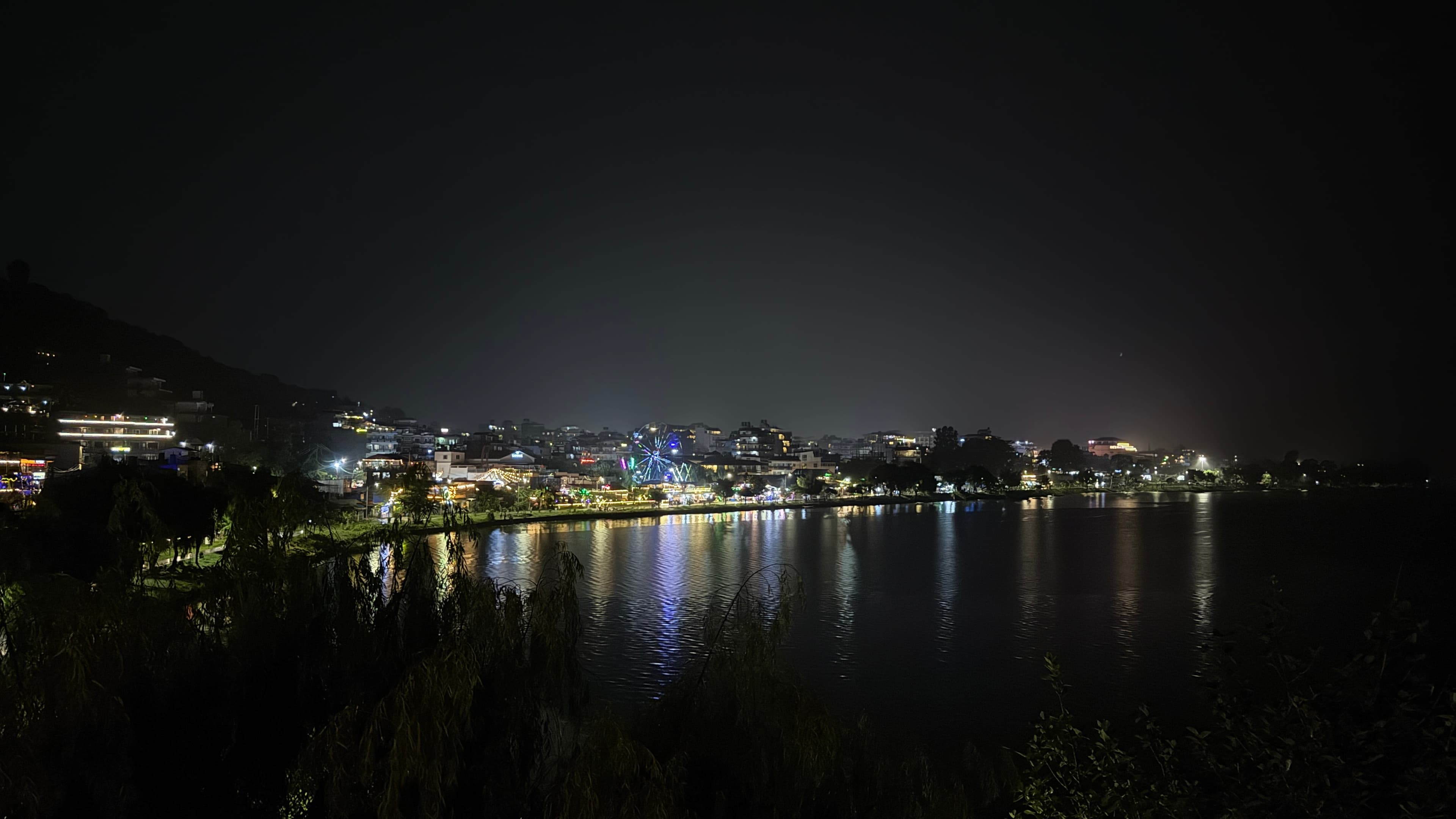 Phewa Lake at night, with the far shore reflected across the water